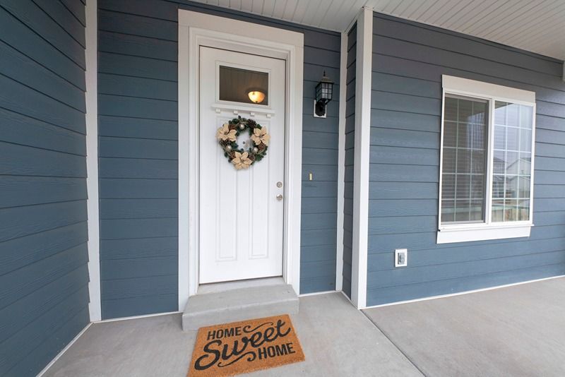 Front_entrance_exterior_with_gray_vinyl_wood_siding_and_concrete_flooring