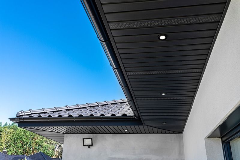 A_modern_graphite_herringbone_roof_lining_is_attached_to_the_trusses,_visible_turned_on_LED_lights.