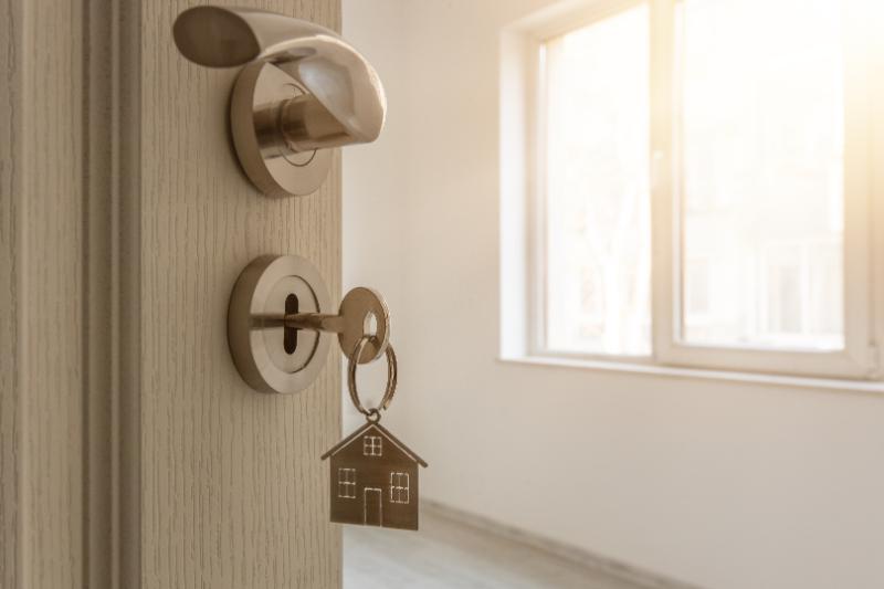 Open_door_to_a_new_home_with_key_and_home_shaped_keychain._Mortgage,_investment,_real_estate,_property_and_new_home_concept