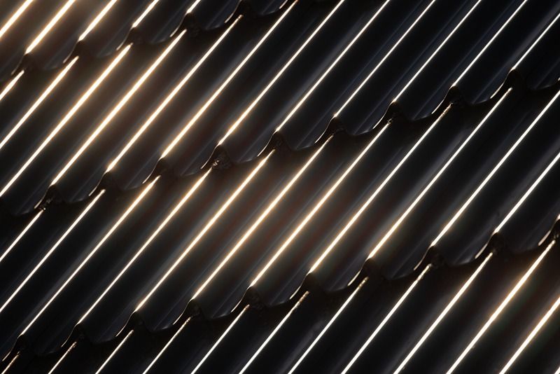 Black_metal_roof_tiling_with_wavy_shape_pattern_and_glowing_sunlight_reflections,_close_up_black_and_white_photo_of_modern_house_roof