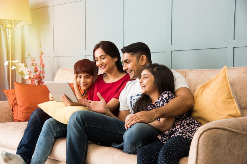 Indian_family_sitting_on_sofa_and_using_smartphone,_laptop_or_tablet,_watching_movie_or_surfing_internet