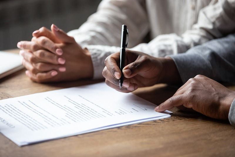 Close_up_of_african_American_husband_put_signature_on_contract_buying_first_house_with_wife,_multiracial_couple_sign_agreement_closing_deal_with_realtor_or_banker,_taking_property_loan_or_mortgage