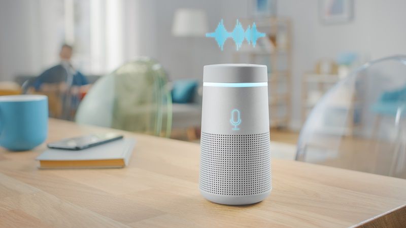 Close_Up_Shot_of_a_Modern_Silver_Wireless_Speaker_Standing_on_a_Table_at_Home_with_Voice_Recording_Hologram