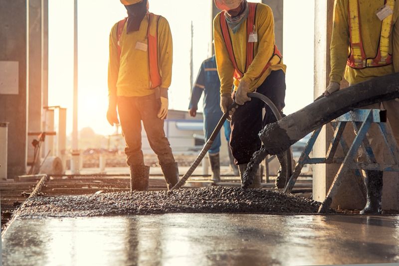 A_construction_worker_pouring_a_wet_concret_at_road_construction_site