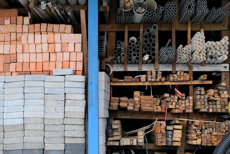 Construction_building_materials_and_industrial_supplies_such_as_bricks,_woods_and_pipes_stacked_and_arranged_for_sale_at_a_hardware_store_front
